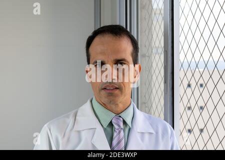medico di 44 anni, sorridente, in un cappotto bianco e cravatta, guardando la macchina fotografica. Foto Stock