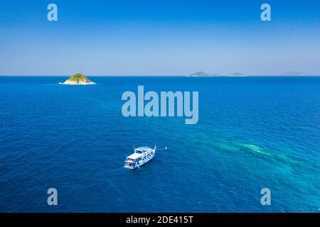 Vista aerea di una barca PER immersioni SUBACQUEE ormeggiata sopra una chiara barriera corallina tropicale nelle Isole Similan in Thailandia. Foto Stock