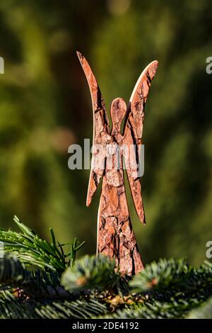Un angelo spartano fatto di legno splendidamente rilasciato di fronte di una foresta verde di conifere Foto Stock