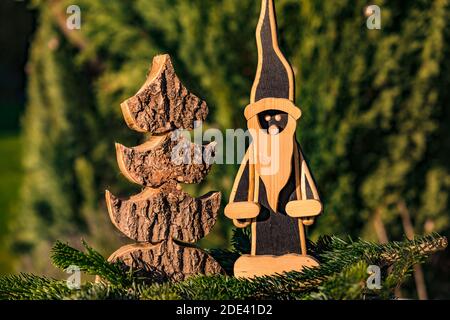 Un classico Babbo Natale in legno accanto a un albero di Natale in legno, splendidamente tagliato di fronte a una verde foresta di conifere Foto Stock