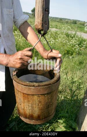 L'uomo nella campagna rumena attingendo l'acqua da un pozzo Foto Stock