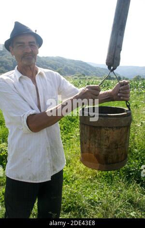 L'uomo nella campagna rumena attingendo l'acqua da un pozzo Foto Stock