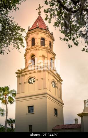 Una vista ravvicinata dell'ora d'oro della campana e della torre dell'orologio, incorniciata da muschi spagnoli e palme della Basilica Cattedrale di Sant'Agostino, una storica Foto Stock
