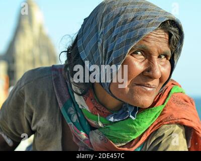 Sospette anziane donne indiane mendicanti con sciarpa sembrano curiosamente e askance al fotografo, di fronte a un tempio indù sotto il cielo blu. Foto Stock