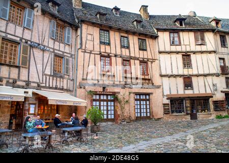 Il piccolo borgo medievale di Conques in Francia. Mostra ai visitatori la sua abbazia-chiesa e case cluster sormontate da tetti di ardesia. Attraversamento di strada stretta Foto Stock