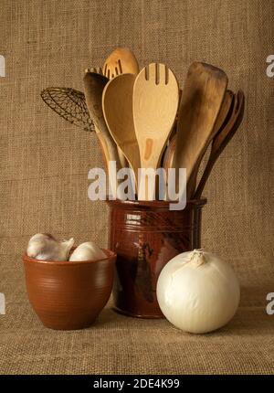 Un assortimento di utensili in legno in un vaso in Pennsylvania, arrangiato con cipolla, e aglio. Foto Stock