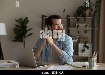 Sorridente sogno di un giovane uomo distratto dal lavoro al computer Foto Stock