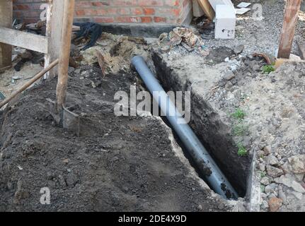 Installazione del tubo fognario nella trincea di terra. Foto Stock