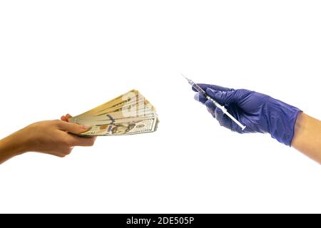 mano in guanto medico tiene una siringa l'altra mano dà soldi. concetto di costo del vaccino del coronavirus. alta qualità Foto Stock