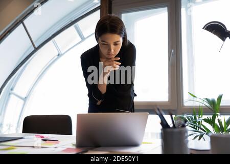 Analisi dei dati di una signora da corsa mista che guarda sullo schermo del laptop Foto Stock