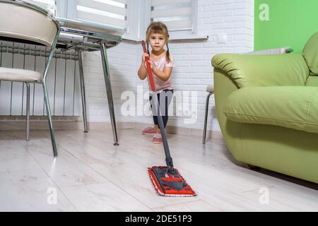 ragazza capretto lava il pavimento nella cucina con un mop Foto Stock