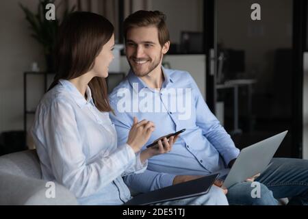 Sorridente motivazione giovani diversi colleghi scambio di informazioni aziendali utilizzando gadget Foto Stock