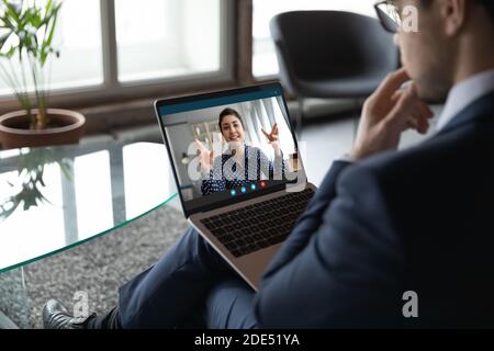 Giovane impiegato di sesso maschile che si collega con una collega indiana tramite videocall Foto Stock