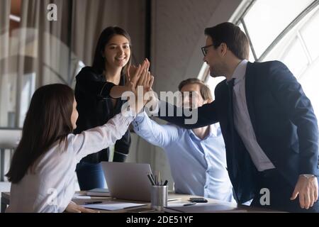Team aziendale entusiasta che unisce i palmi in un briefing in ufficio Foto Stock