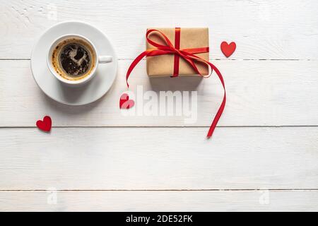 Creative Vista dall'alto piatto composizione romantica. Tazza per caffè espresso caldo con cuori di regalo rossi e scatola regalo artigianale. Concetto o compleanno o valentine Foto Stock