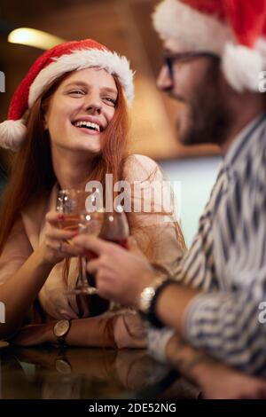 drunk red head con cappello di santa tostando con il suo partner a. nuovo anno di celevrazione Foto Stock