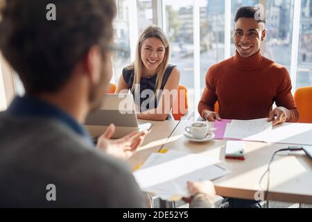 Una commissione d'impresa che ha una piacevole intervista in un'atmosfera rilassata con un candidato per una posizione di lavoro. Persone, lavoro, azienda, business concept. Foto Stock