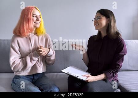 Ragazza teen che dà l'intervista al lavoratore sociale. Psicologo scolastico che parla con lo studente Foto Stock