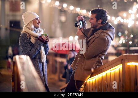 giovane caucasico scattando una foto della sua ragazza tenendo tazza di tè all'aperto con fotocamera retrò Foto Stock