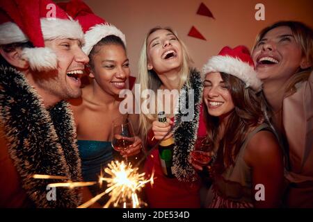 gruppo di persone a festa di nuovo anno, bere alcol, indossare cappelli santa Foto Stock