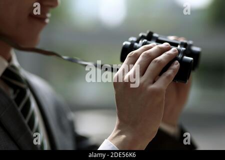 Primo piano di un uomo d'affari che tiene binocoli Foto Stock