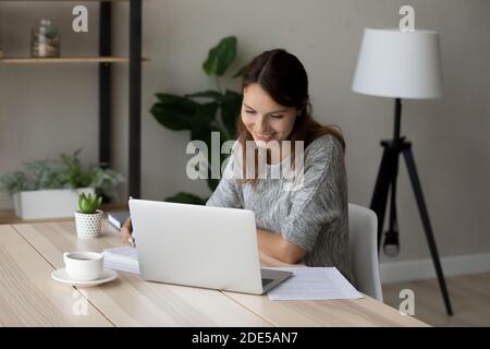 Felice giovane donna europea che guarda la lezione educativa. Foto Stock
