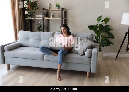 Giovane donna araba indiana concentrata in cuffia in attesa di videochiamata. Foto Stock