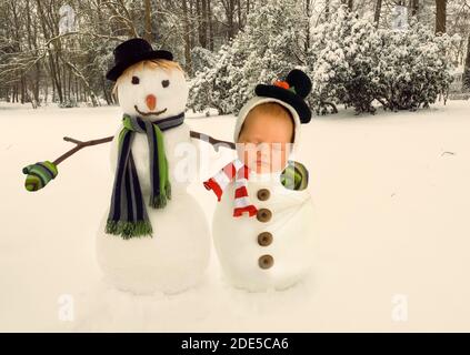 Immagine composita con un vero pupazzo di neve e un bambino addormentato avvolti in outfit per pupazzi di neve Foto Stock