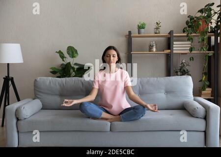 Giovane e pacifica donna araba indiana che fa esercizi di respirazione yoga. Foto Stock