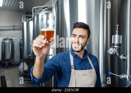 Birreria professionale che assaggia la birra in vetro alla produzione Foto Stock