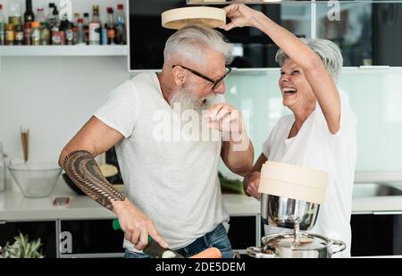 Crazy senior couple cooking insieme a casa - gioioso anziano Stile di vita e concetto di nutrizione alimentare - Focus principale sull'uomo faccia Foto Stock