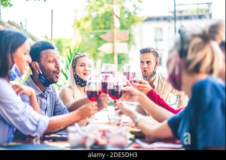 Amici che tostano vino rosso al bar ristorante all'aperto con viso Maschera giù - nuovo concetto di stile di vita normale con la gente felice Divertirsi insieme - Focus o Foto Stock