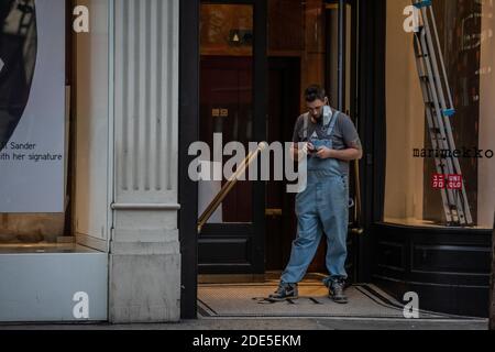 Il tradesman si trovava all'ingresso di un negozio in fase di ristrutturazione su Oxford Street durante l'ultimo fine settimana di Coronavirus Lockdown 2, Londra, Inghilterra, Regno Unito Foto Stock