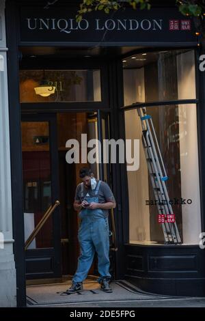 Il tradesman si trovava all'ingresso di un negozio in fase di ristrutturazione su Oxford Street durante l'ultimo fine settimana di Coronavirus Lockdown 2, Londra, Inghilterra, Regno Unito Foto Stock