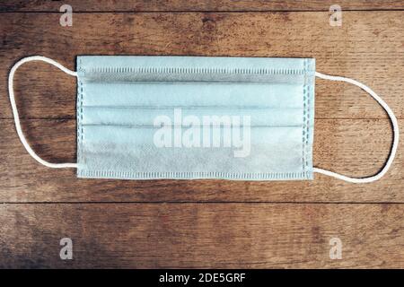 La maschera medica blu giace su una vecchia struttura di sfondo della tavola di legno marrone. Foto Stock