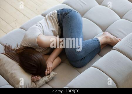 Vista dall'alto infelice giovane donna depressa sdraiata sul divano Foto Stock