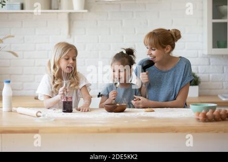 Madre felice e due adorabili figlie che si divertono in cucina Foto Stock