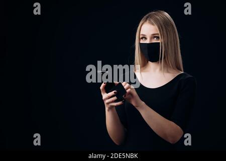Biondo in maschera con carta di credito e cellulare per lo shopping Foto Stock