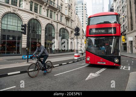 Strade e strade tranquille nella città nel centro di Londra con solo un autobus rosso per i trasporti pubblici, e un ciclista su una bicicletta durante il blocco Coronavirus Covid-19 in Inghilterra, Regno Unito, Europa Foto Stock