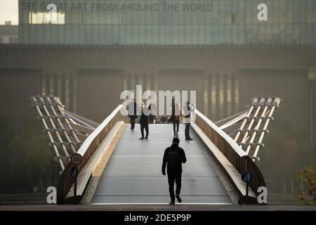 Persone che camminano sul Millennium Bridge al tramonto, con la Tate Modern Gallery a Londra, ha preso in Inghilterra durante il Lockdown Coronavirus Covid-19, Regno Unito, Europa Foto Stock