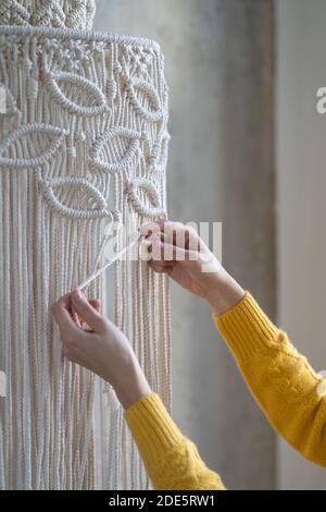 Primo piano di donna freelance che lavora su pezzo di macrame semilavorato, tesse paralume lampada per lampadario. Hobby delle donne. Foto Stock