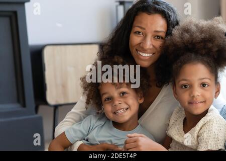 Tutor femminile nero che guarda la macchina fotografica che si pone con gli allievi amati Foto Stock