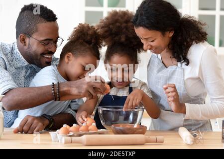 Amando amichevole famiglia afro americana che mescola l'impasto per dolci fatti in casa Foto Stock