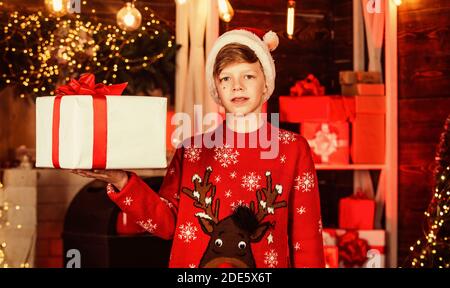 Ho ho ho. Egli ha xmas presente. le migliori vacanze invernali. Felice adolescente di celebrare la festa di capodanno. Little Boy in rosso le renne maglione. kid a santa claus hat divertirsi a casa. Buon Natale a tutti. Foto Stock