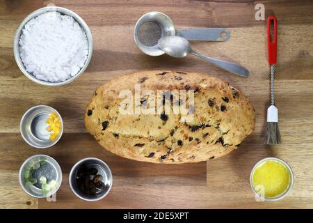Stollen di Natale sassone tradizionale appena sfornato con alcuni ingredienti da forno su sfondo di legno Foto Stock