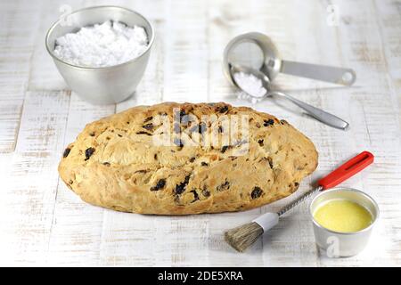 Stollen di Natale sassone tradizionale appena sfornato con alcuni ingredienti da forno da rifinire con zucchero in polvere Foto Stock
