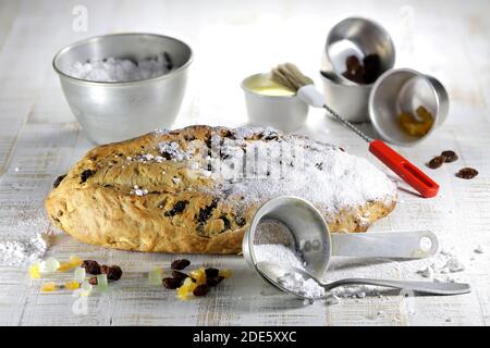 Stollen di Natale sassone tradizionale appena sfornato con alcuni ingredienti da forno da rifinire con zucchero in polvere Foto Stock
