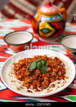 Il piatto orientale guiru lagman è noodle fatte in casa fritte con carne, verdure ed erbe. Cucina orientale Foto Stock