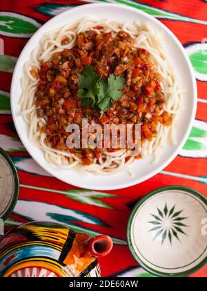 Il piatto orientale guiru lagman è noodle fatte in casa fritte con carne, verdure ed erbe. Cucina orientale Foto Stock