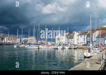 WEYMOUTH, Regno Unito - 28 AGOSTO 2020: Grandi quantità di barche lungo il porto di Weymouth a Dorset, Inghilterra. La gente può anche essere vista. Foto Stock